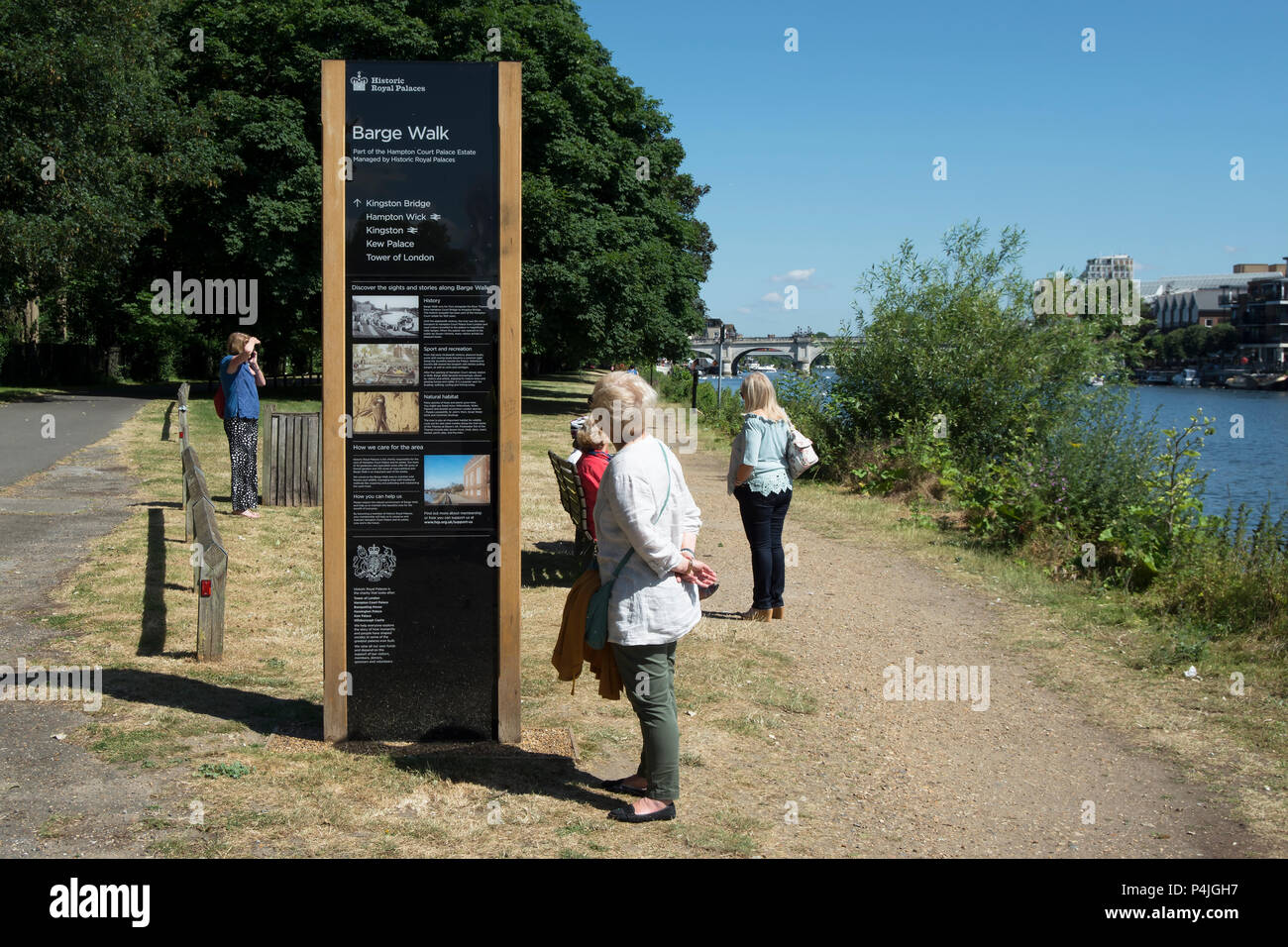 a woman examines a wayfinding and information pillar sign at barge walk