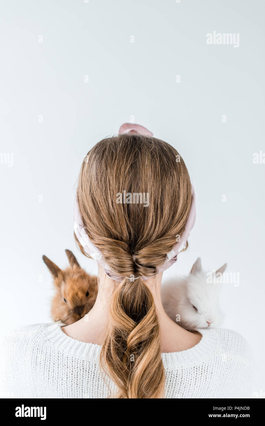 rear view of girl holding adorable furry rabbits isolated on white ...