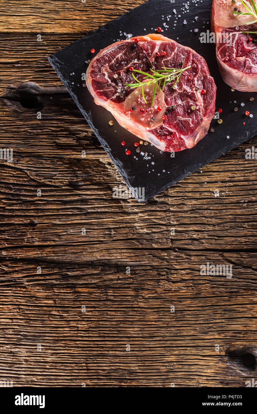 Two pieces raw beef shank on slate board and wooden table.. Stock Photo