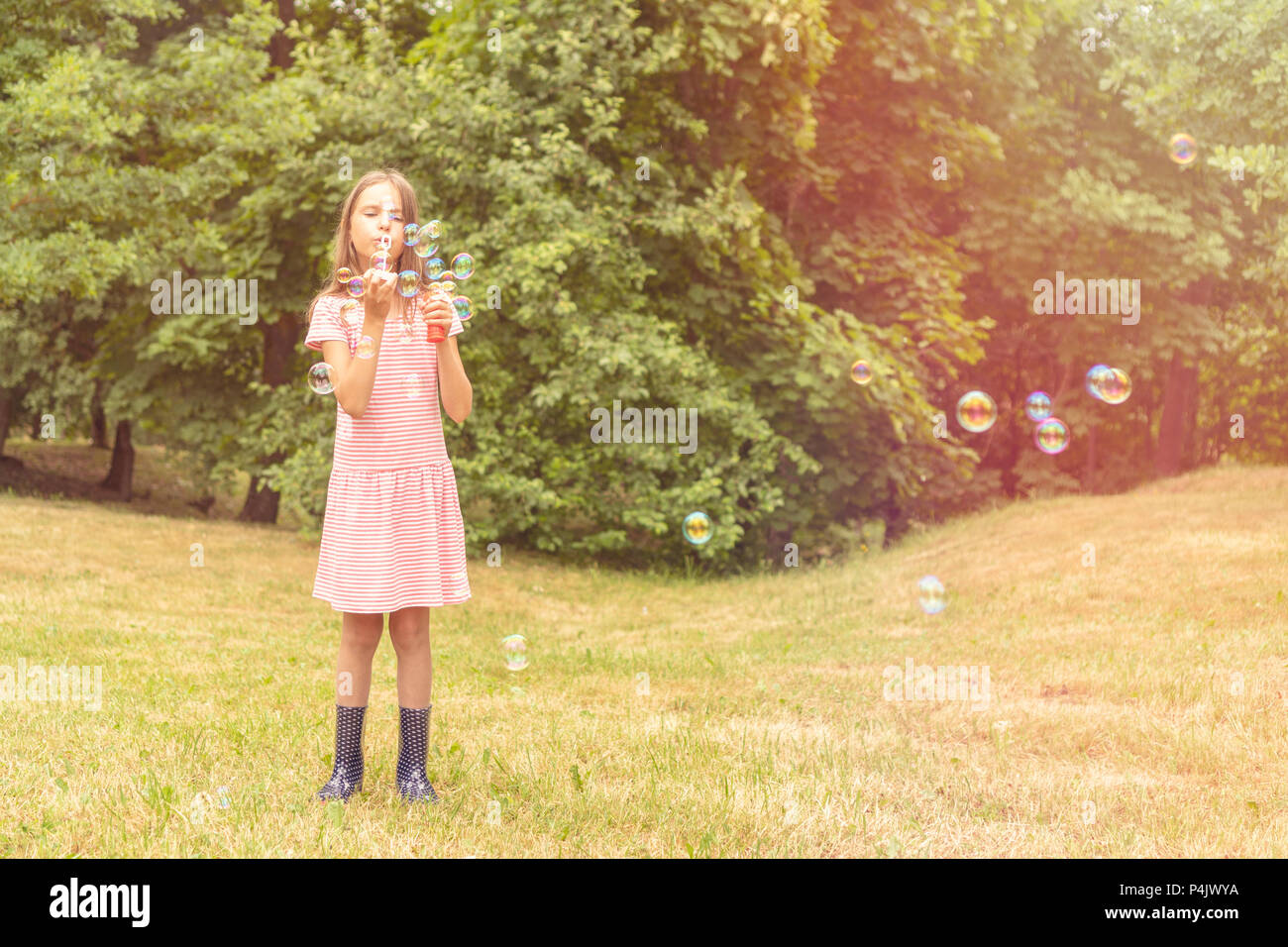 Cute little girl playing with bubbles in a public park Stock Photo - Alamy