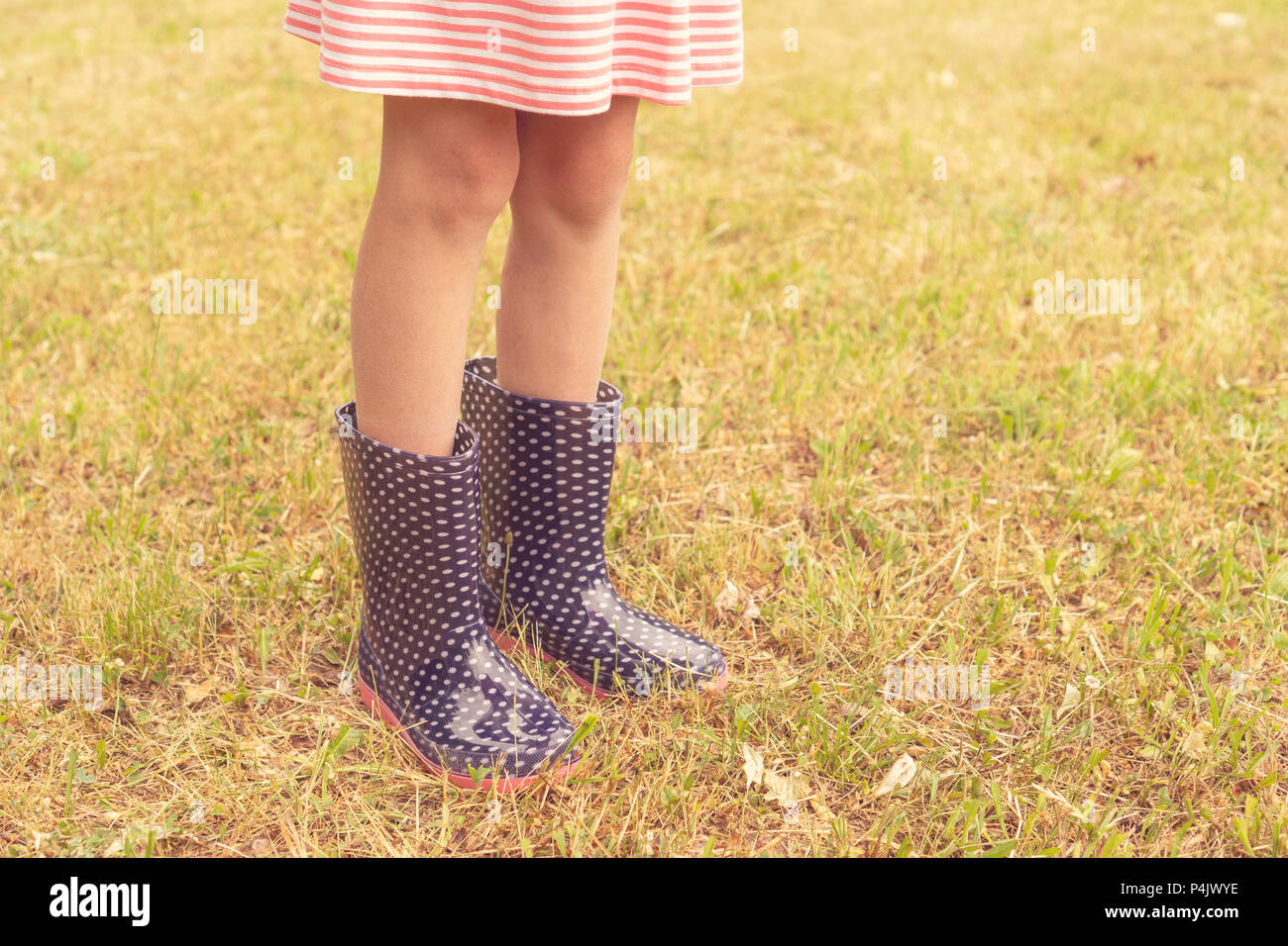 Legs of girl standing on a wet lawn wearing rain boots Stock Photo Alamy