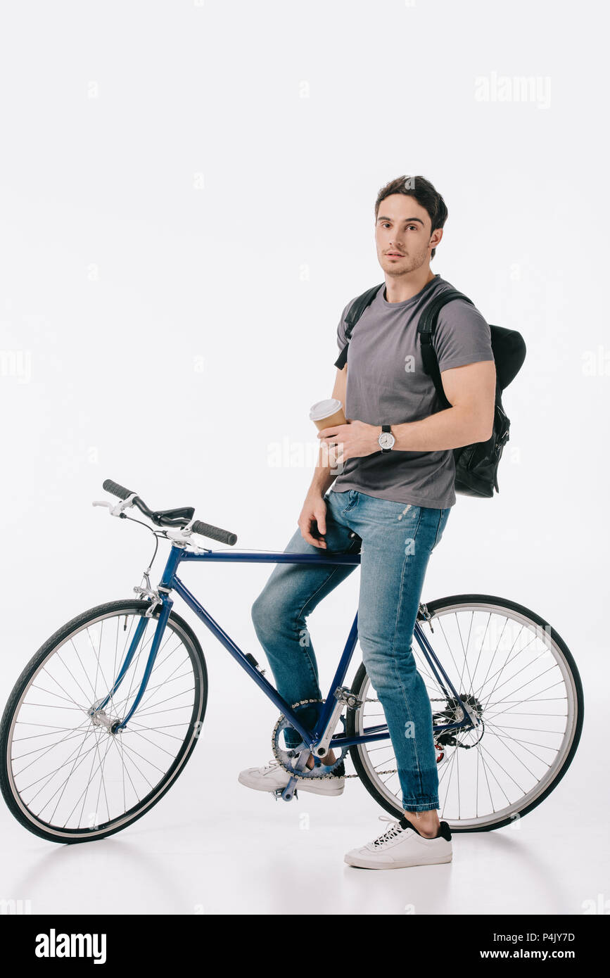 handsome student sitting on bicycle and holding coffee to go on white Stock Photo