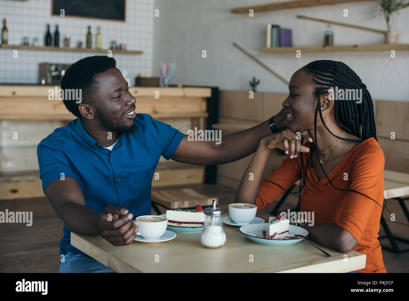 happy african american couple sitting at table with cups of coffee and ...