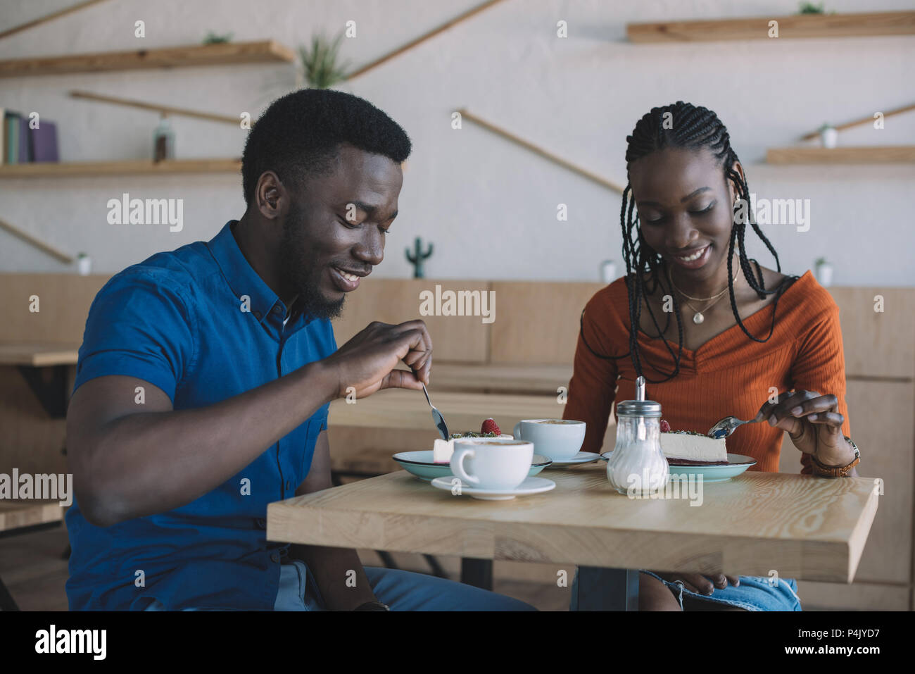 smiling african american couple at table with cups of coffee and ...