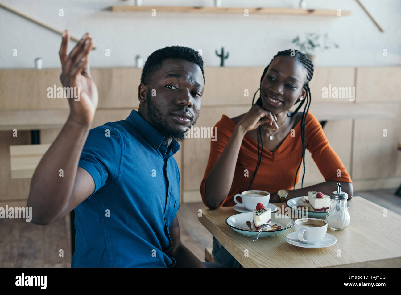 african american couple sitting at table with cups of coffee and ...