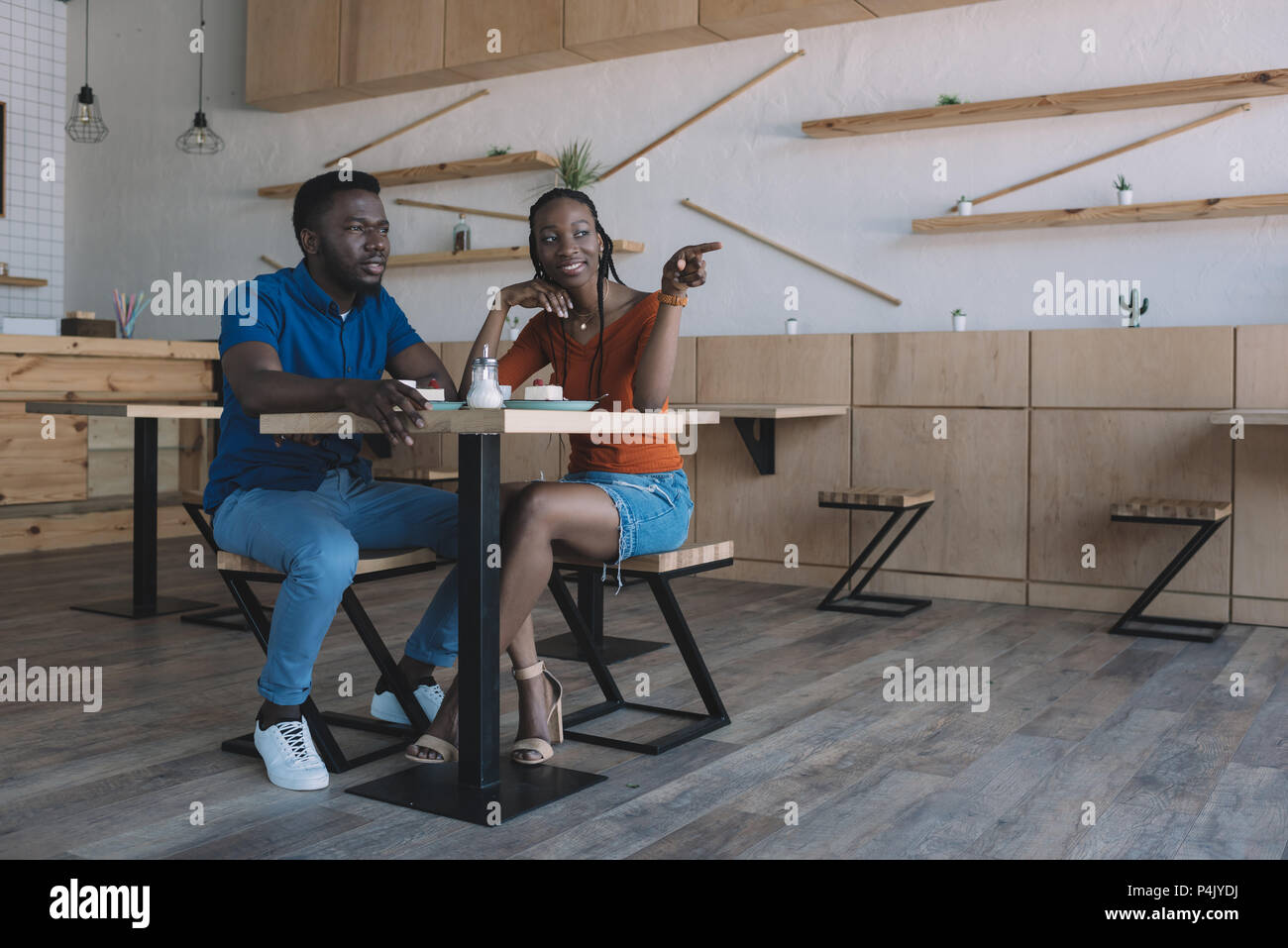 smiling african american couple sitting at table with cups of coffee ...