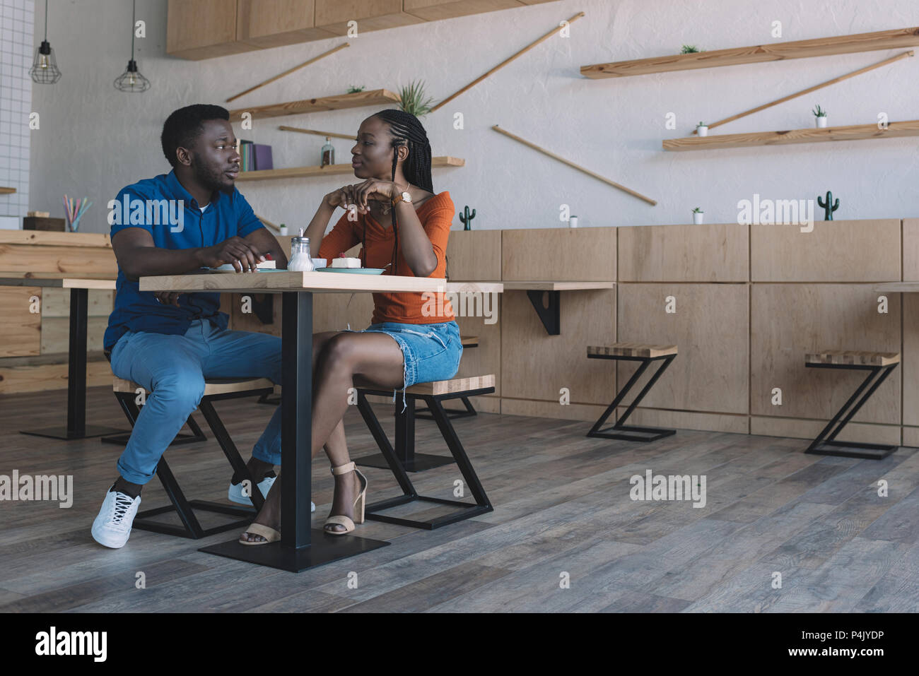 african american couple talking at table with cups of coffee and ...