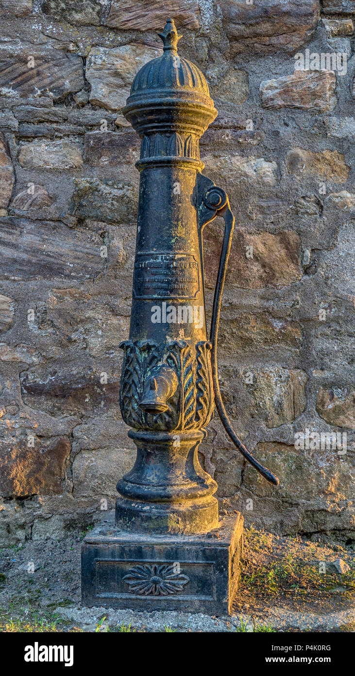 This elegant cast-iron baluster hand pump sits against a wall opposite a block of flats, just off the main square in Blackness village, on the souther Stock Photo