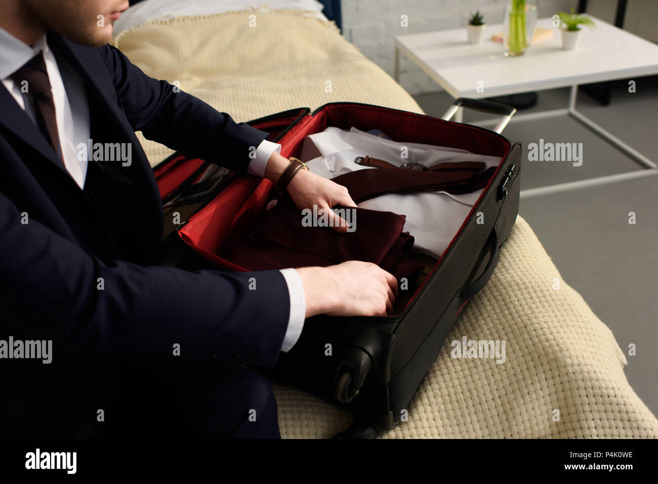 https://c8.alamy.com/comp/P4K0WE/cropped-view-of-businessman-in-suit-packing-clothes-in-travel-bag-P4K0WE.jpg