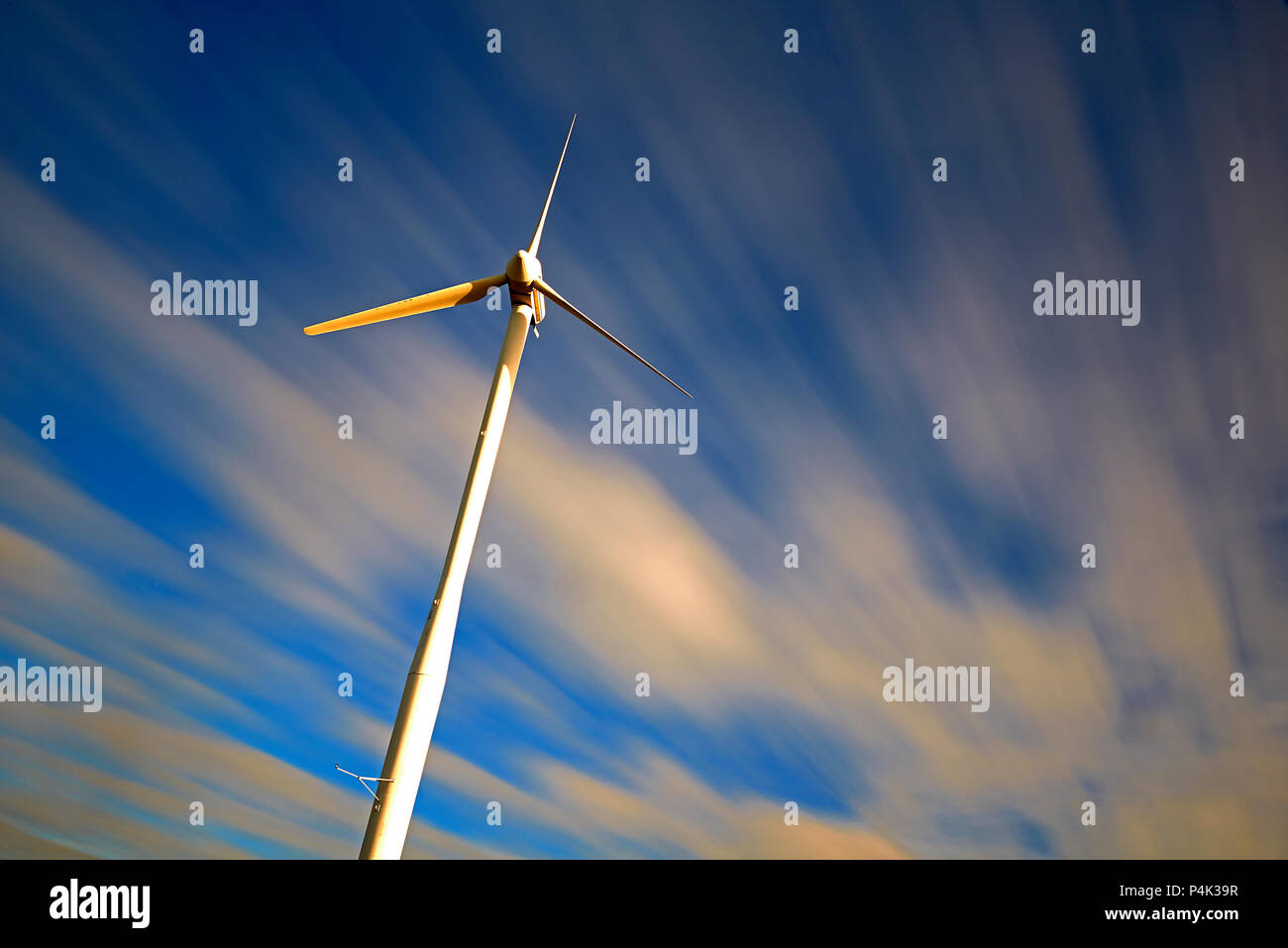 Long exposure of wind turbines with the movement of the clouds made visible to show the power of the wind to generate renewable clean energy Stock Photo