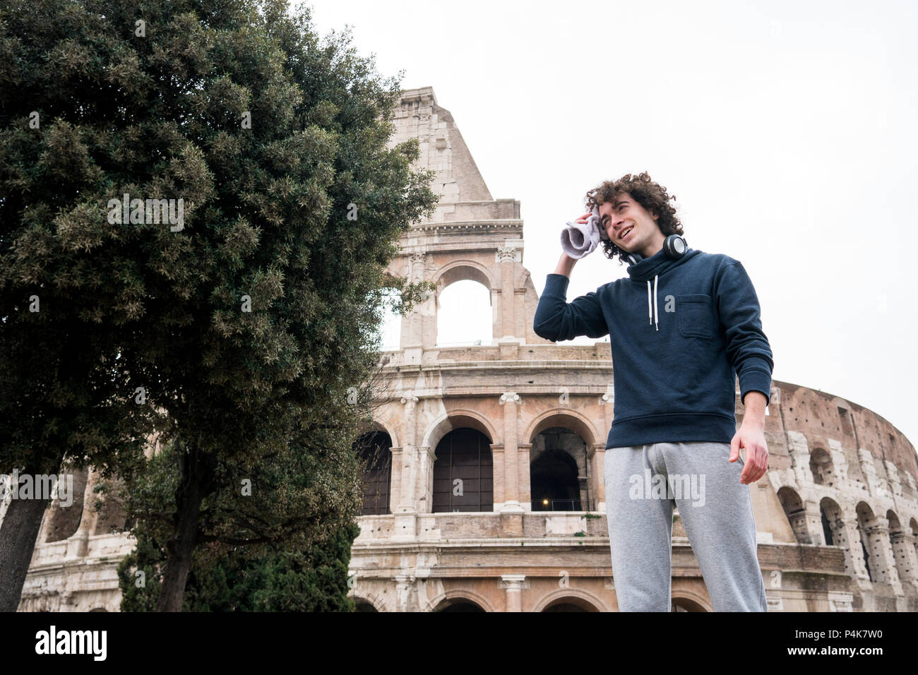 Handsome young sportsman relaxing after training wiping sweat with a towel in front of Colosseum in Rome Stock Photo