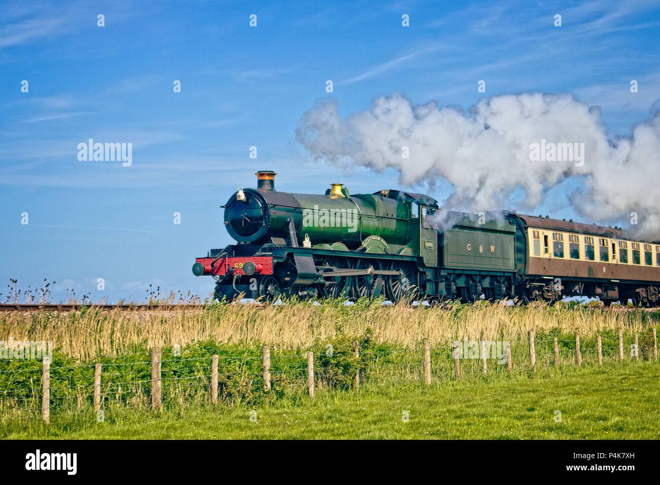 Raveningham Hall steam engine in steam pulling carriages across the embankment having departed Blue Anchor station in North Somerset. Stock Photo