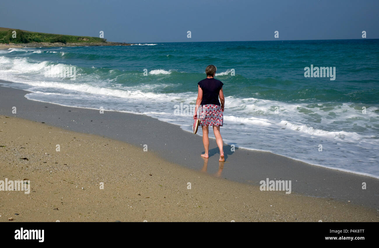 A woman walks along Towan Beach, on the Roseland Peninsula, Cornwall, Britain on June 9, 2018 Stock Photo