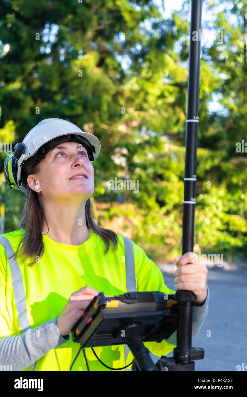 Close up of woman in reflective clothing using GPS land surveying tool with screen Stock Photo