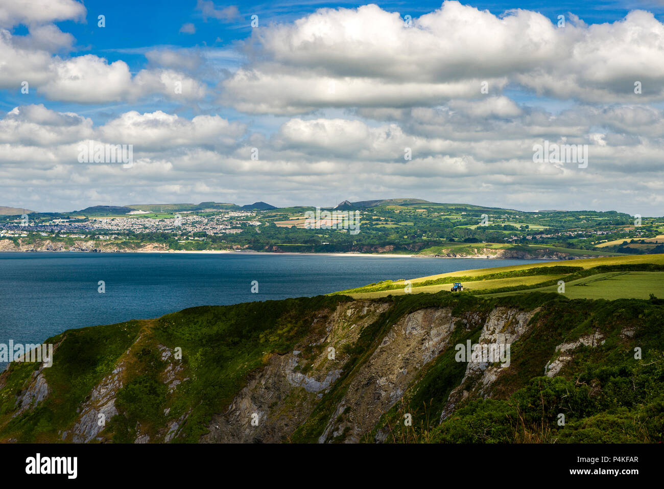 A shaft of sunlight beams down onto a farmer as he plough cliff top fields. Stock Photo