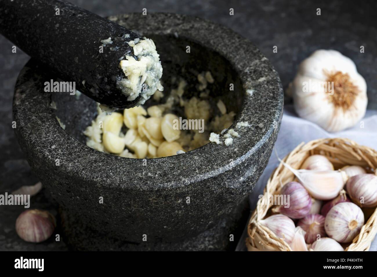 Mashed garlic in grey granite mortar with pestle, standing on dark sheet metal Stock Photo Alamy