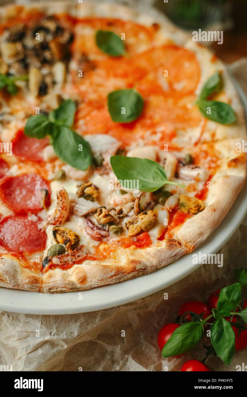 Pizza Quattro Stagioni with salami, seafood, tomatoes and mushrooms