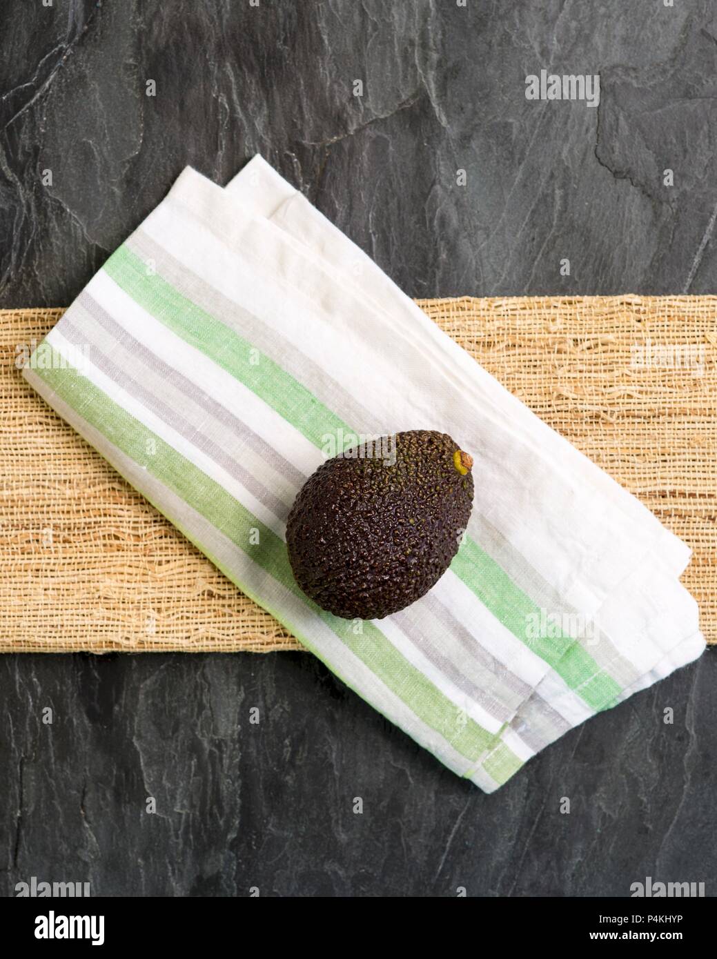 A whole avocado on a fabric napkin (seen from above) Stock Photo
