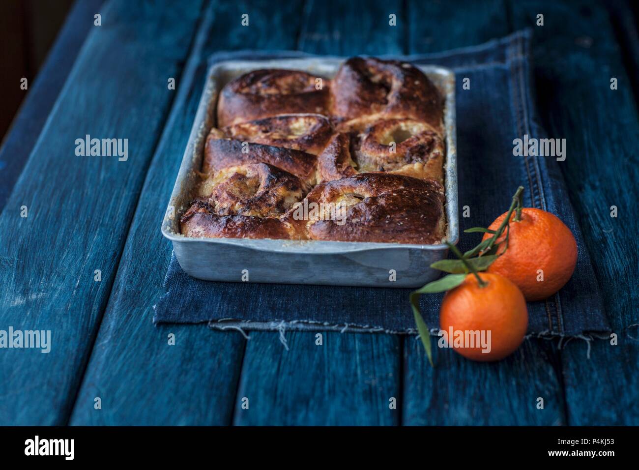 Apple and cinnamon buns in a baking dish next to mandarins Stock Photo