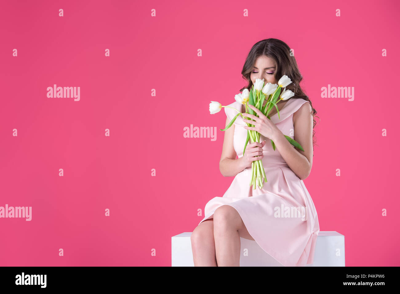 attractive girl sniffing bouquet of tulips isolated on pink Stock Photo