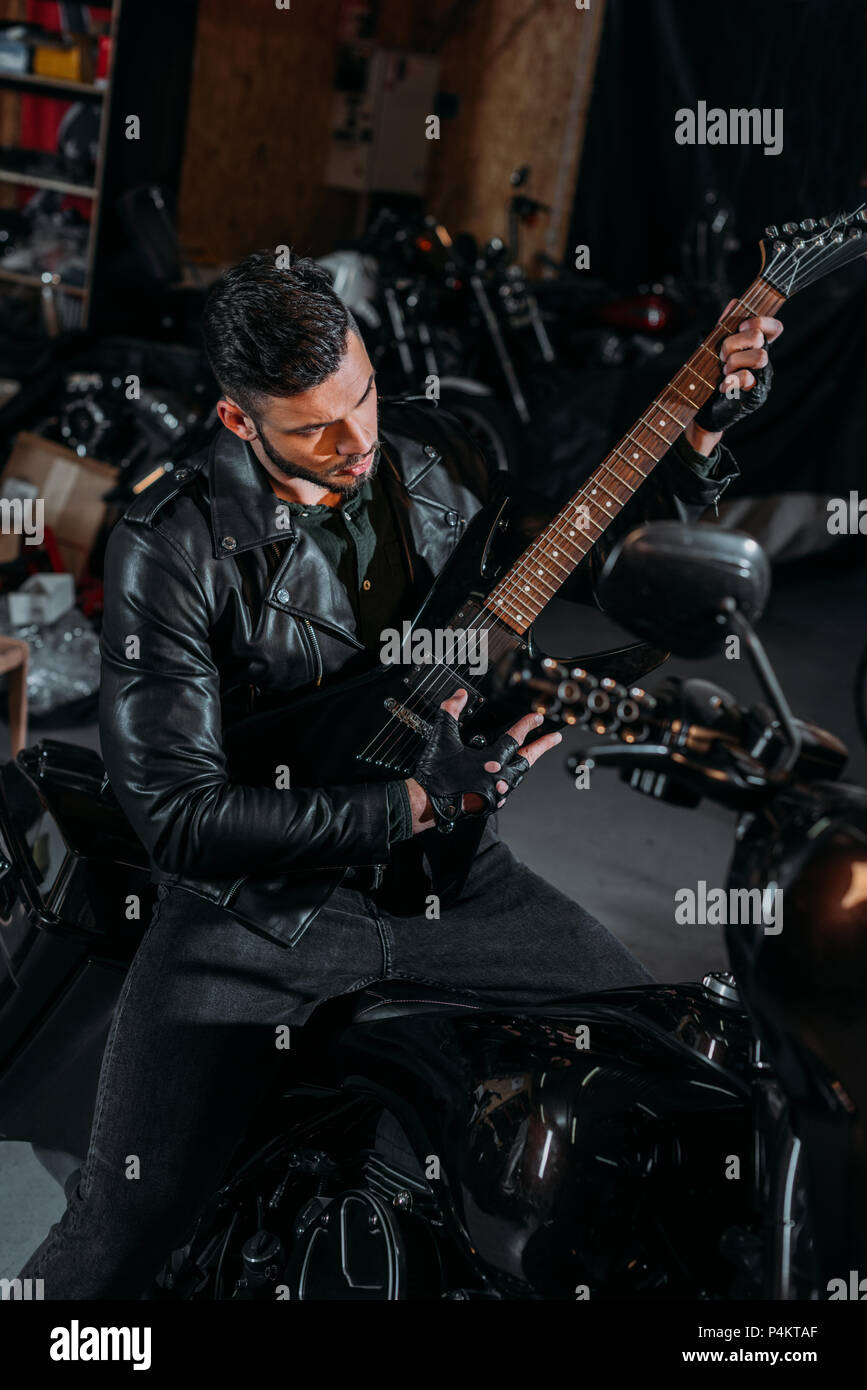 handsome young man playing guitar while sitting on bike at garage Stock  Photo - Alamy