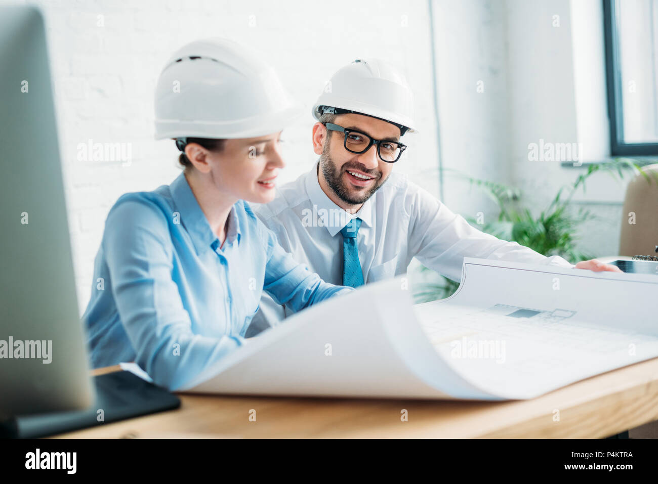 smiling architects working with building plan at office Stock Photo