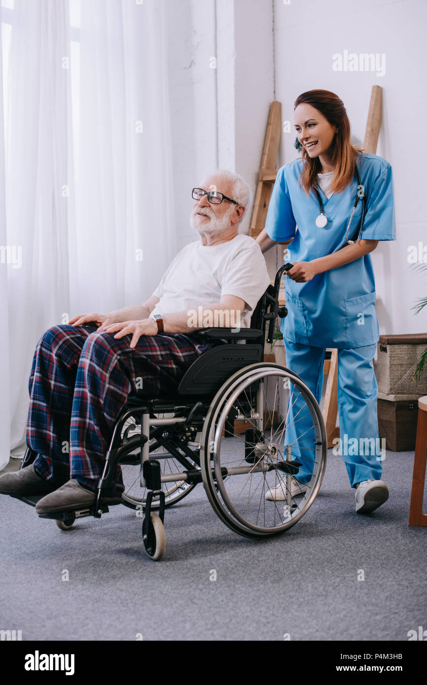 Nurse pushing wheelchair with senior patient Stock Photo - Alamy