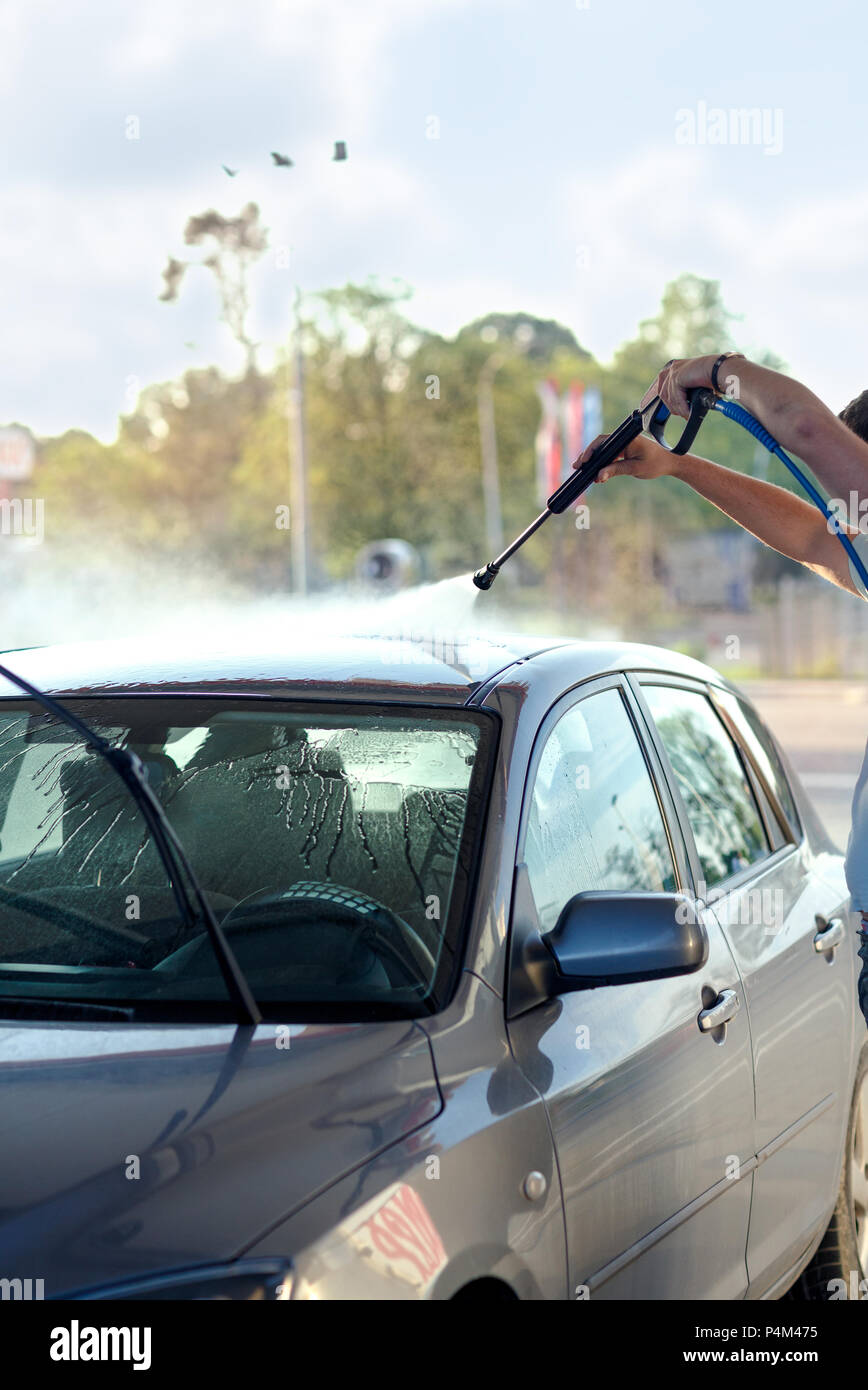 man washing his car under high pressure water outdoors Stock Photo Alamy
