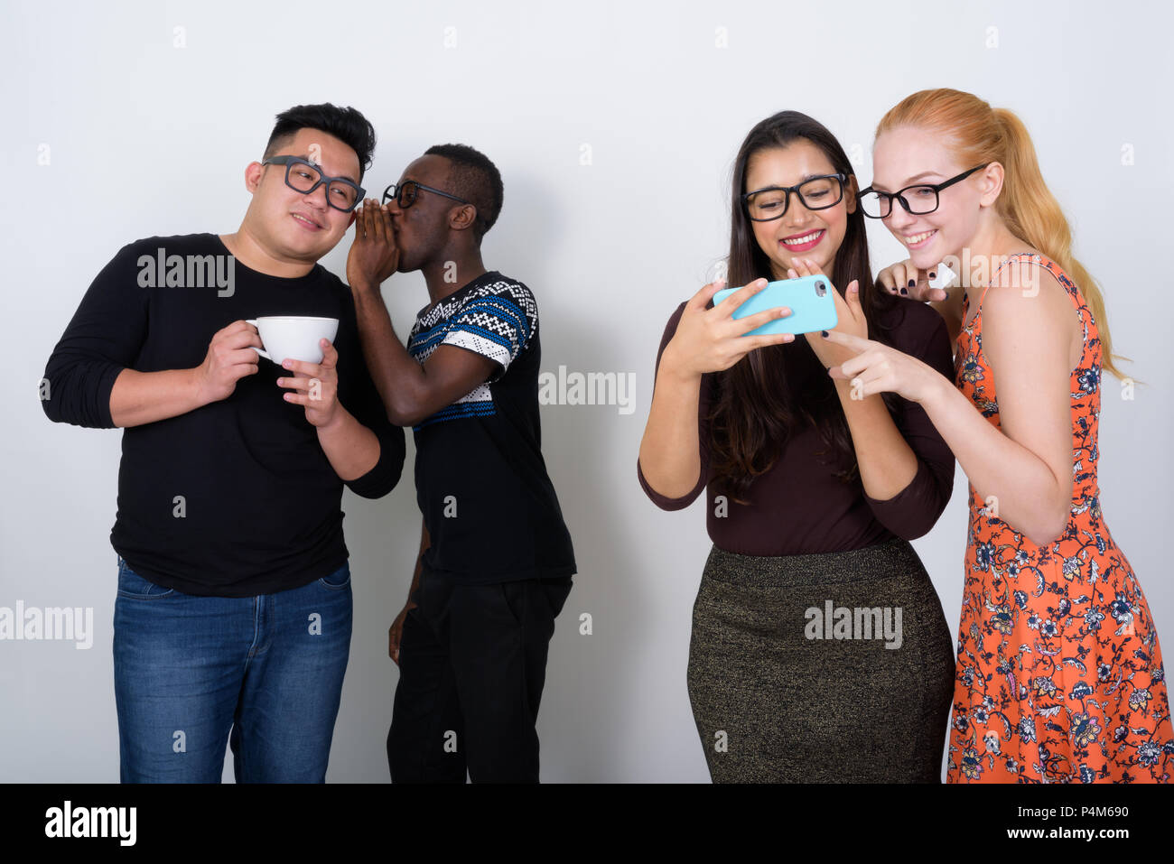 Happy diverse group of multi ethnic friends smiling while using  Stock Photo