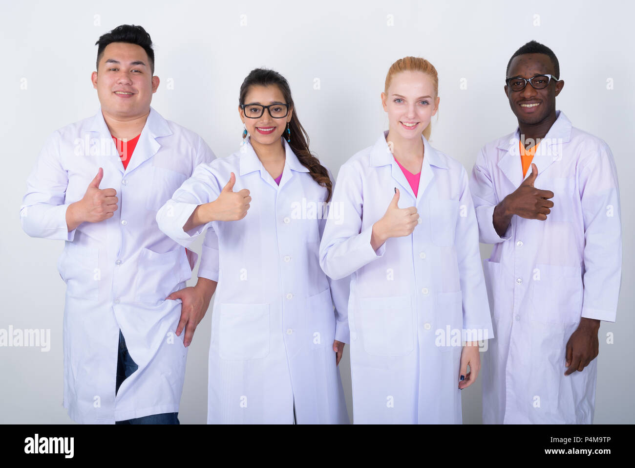 Studio shot of happy diverse group of multi ethnic doctors smiling while giving thumb up together Stock Photo