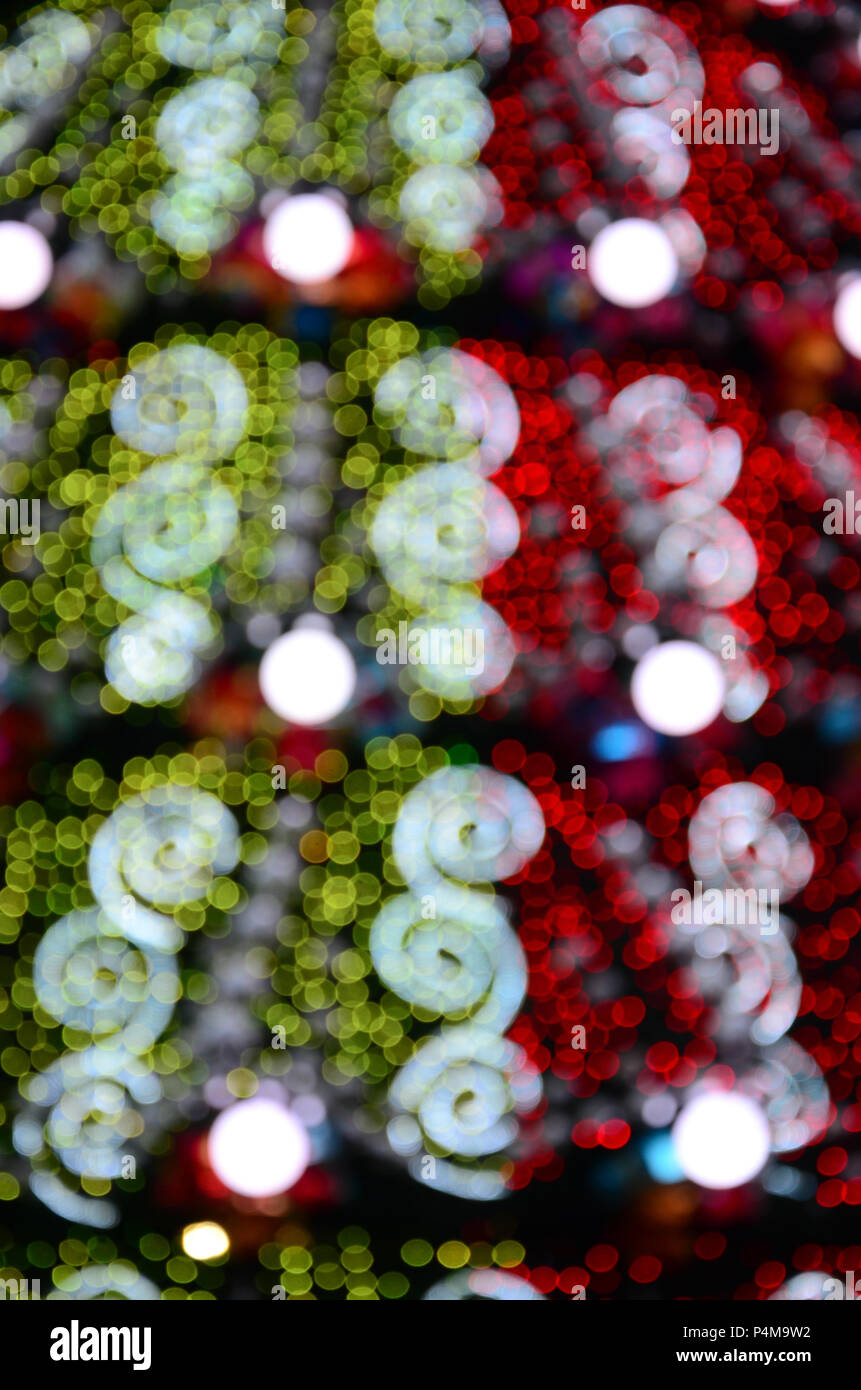 Blurred fragment of a huge Christmas tree with many luminous lamps ...