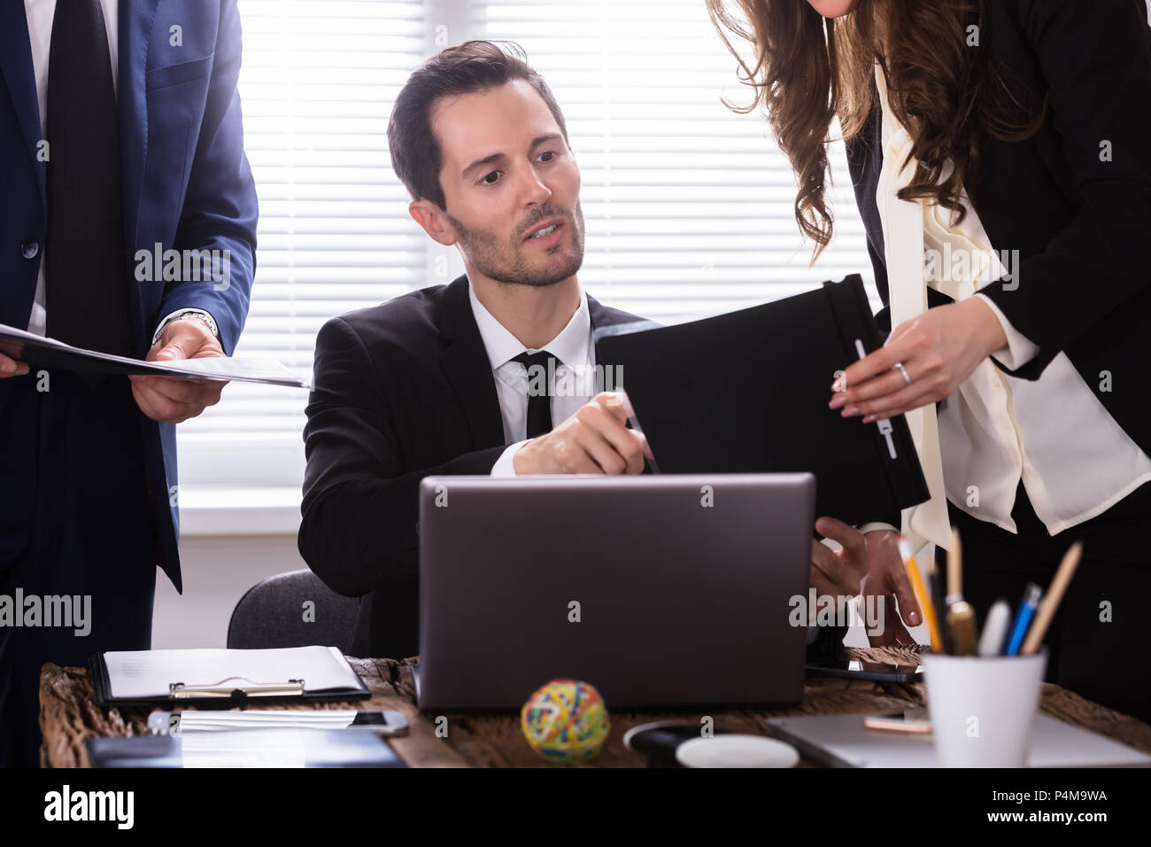 Young Businessman Looking At Document Shown By Partner Stock Photo