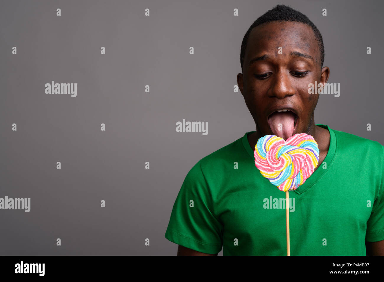 Young African man wearing green shirt against gray background Stock Photo