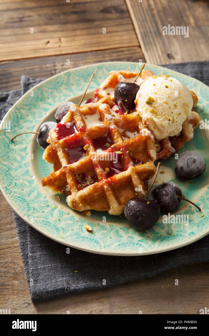 Round Belgian waffles with cherries, cherry sauce and vanilla ice cream Stock Photo