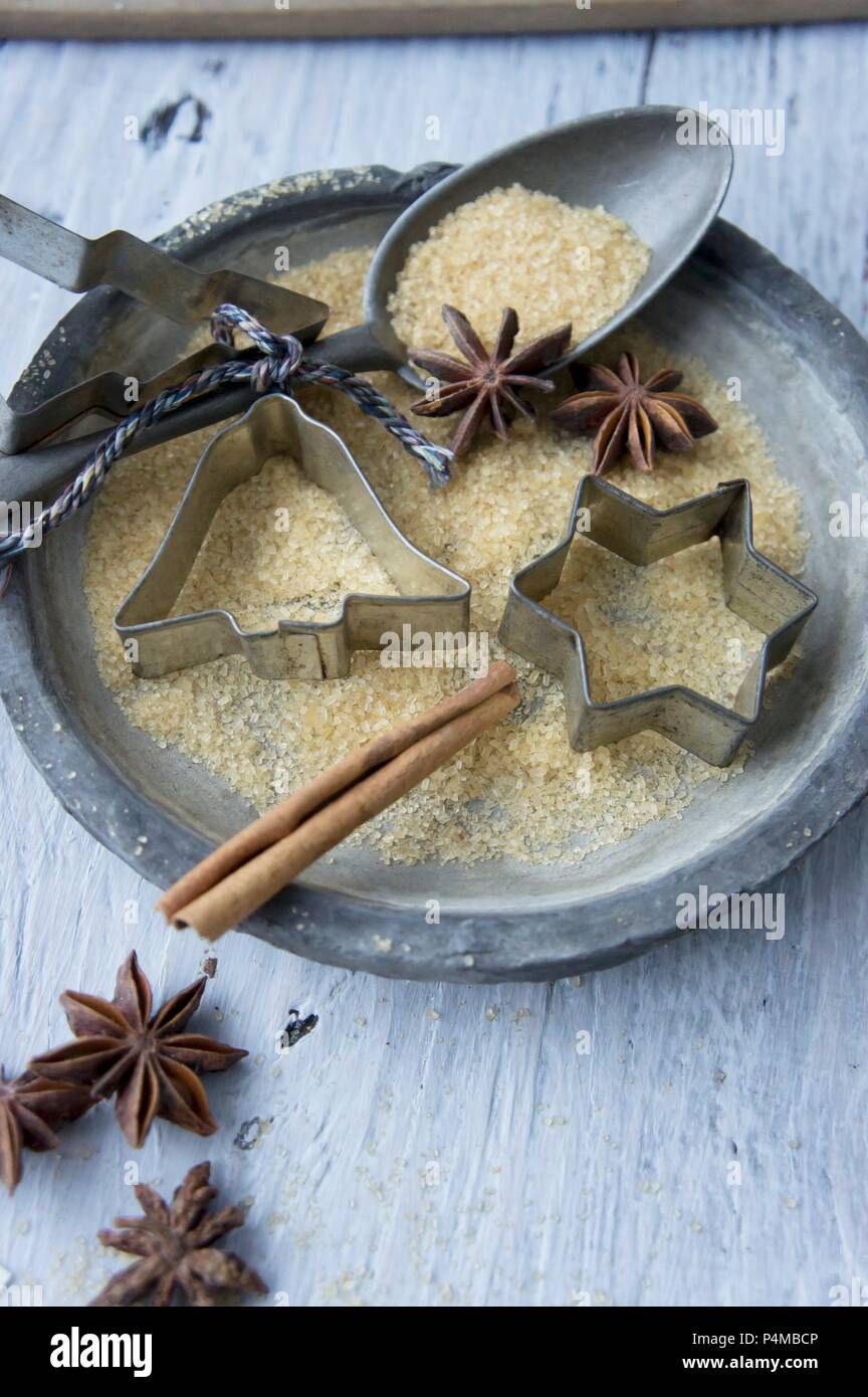 A plate with cookie cutters, a spoon, sugar, star anise and a cinnamon stick Stock Photo