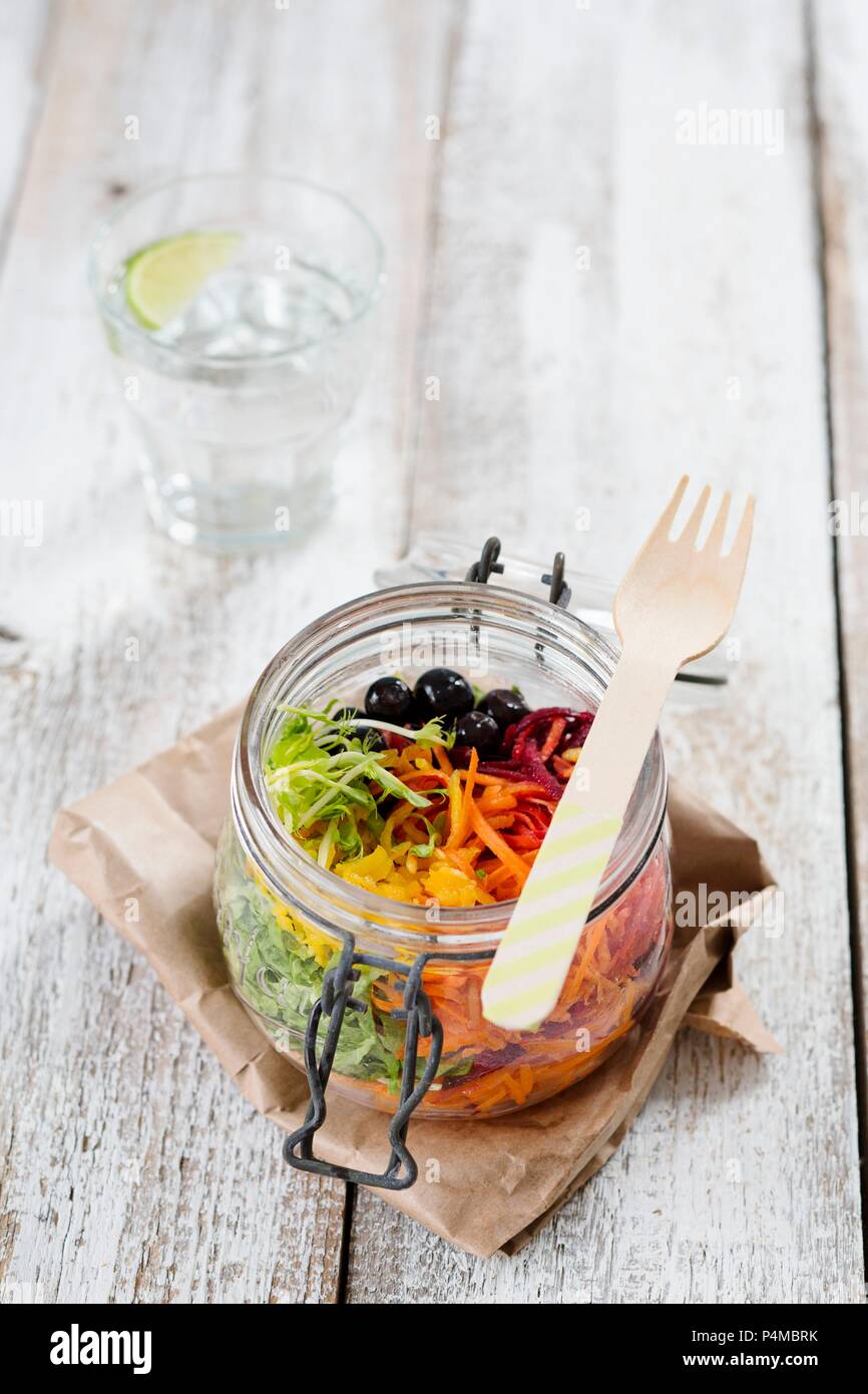 Rainbow salad in an open glass jar with beetroot, carrots, yellow pepper, lettuce and blueberries Stock Photo