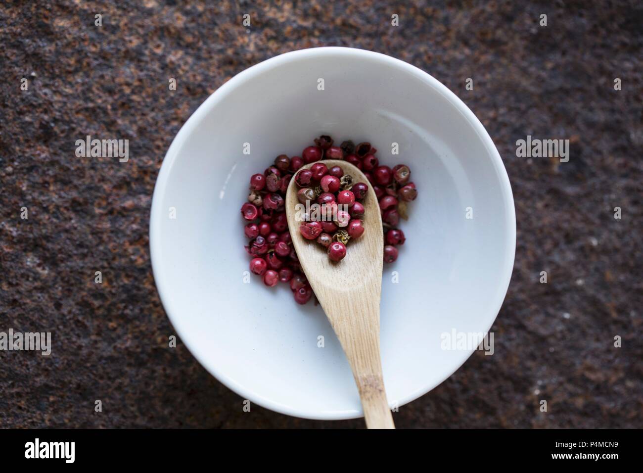 Red peppercorns with a wooden spoon in a bowl (seen from above) Stock Photo