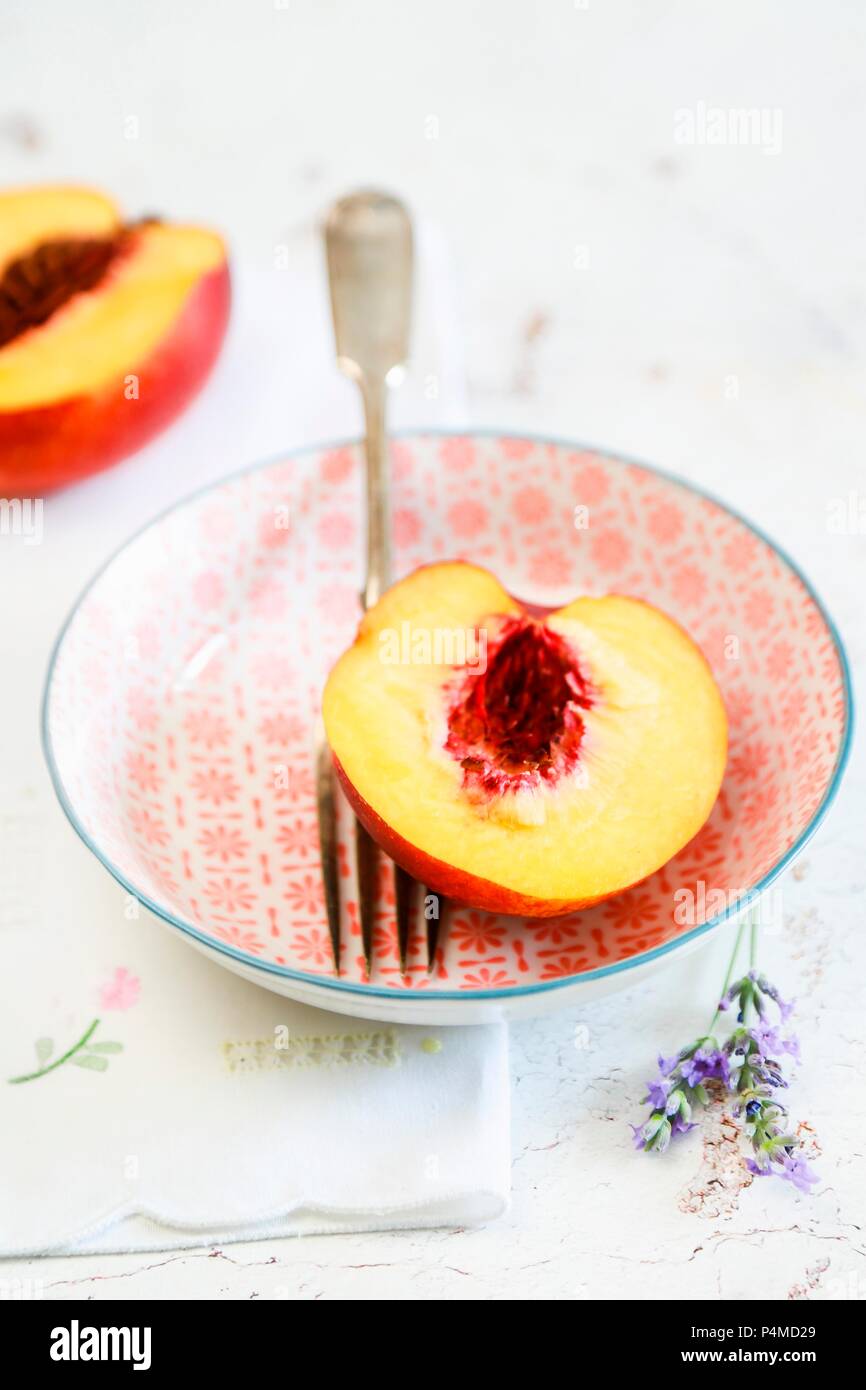 Half a peach in a bowl with a fork Stock Photo