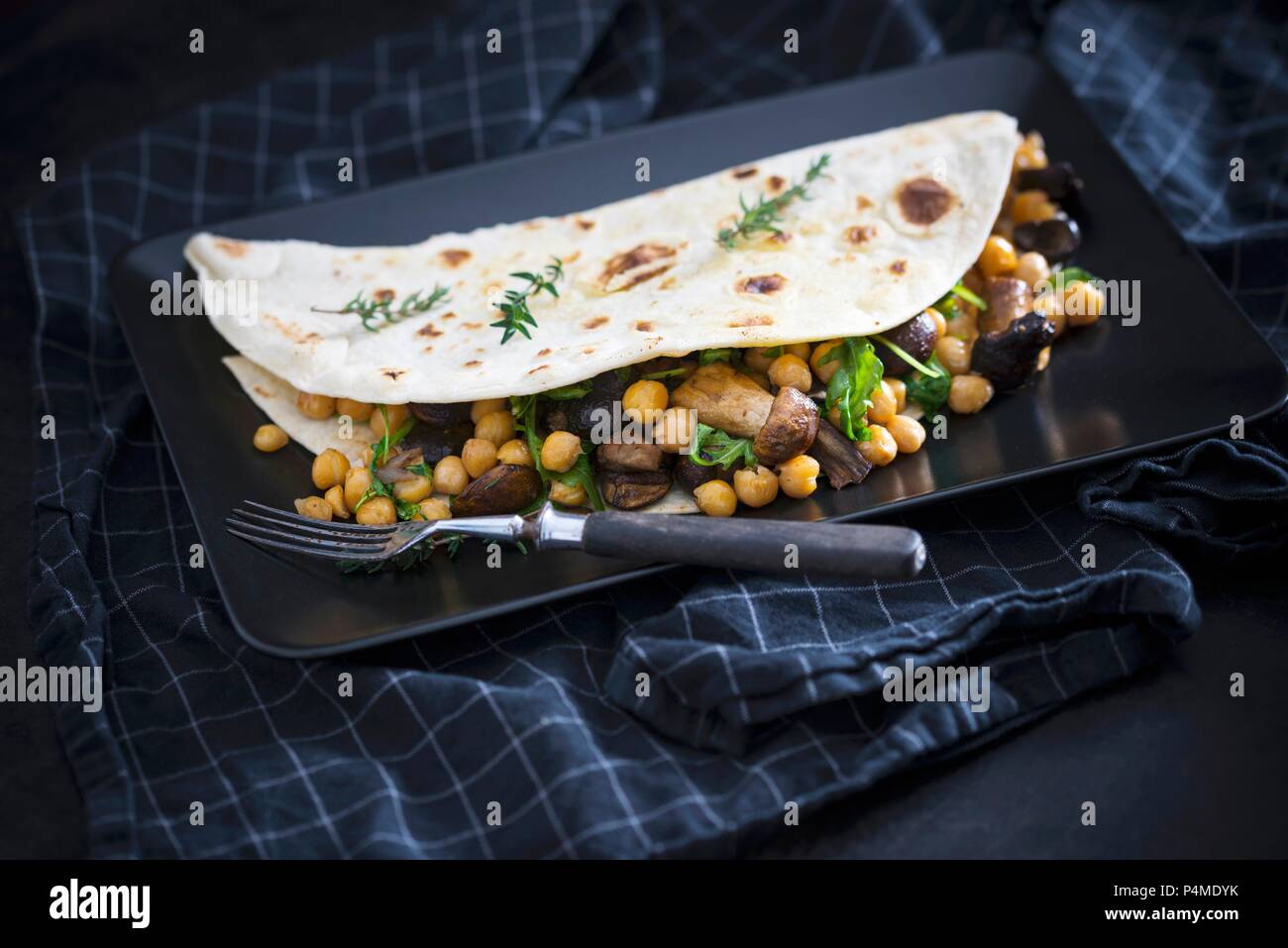 A vegan wheat flatbread stuffed with chickpeas, mushrooms and rocket Stock Photo