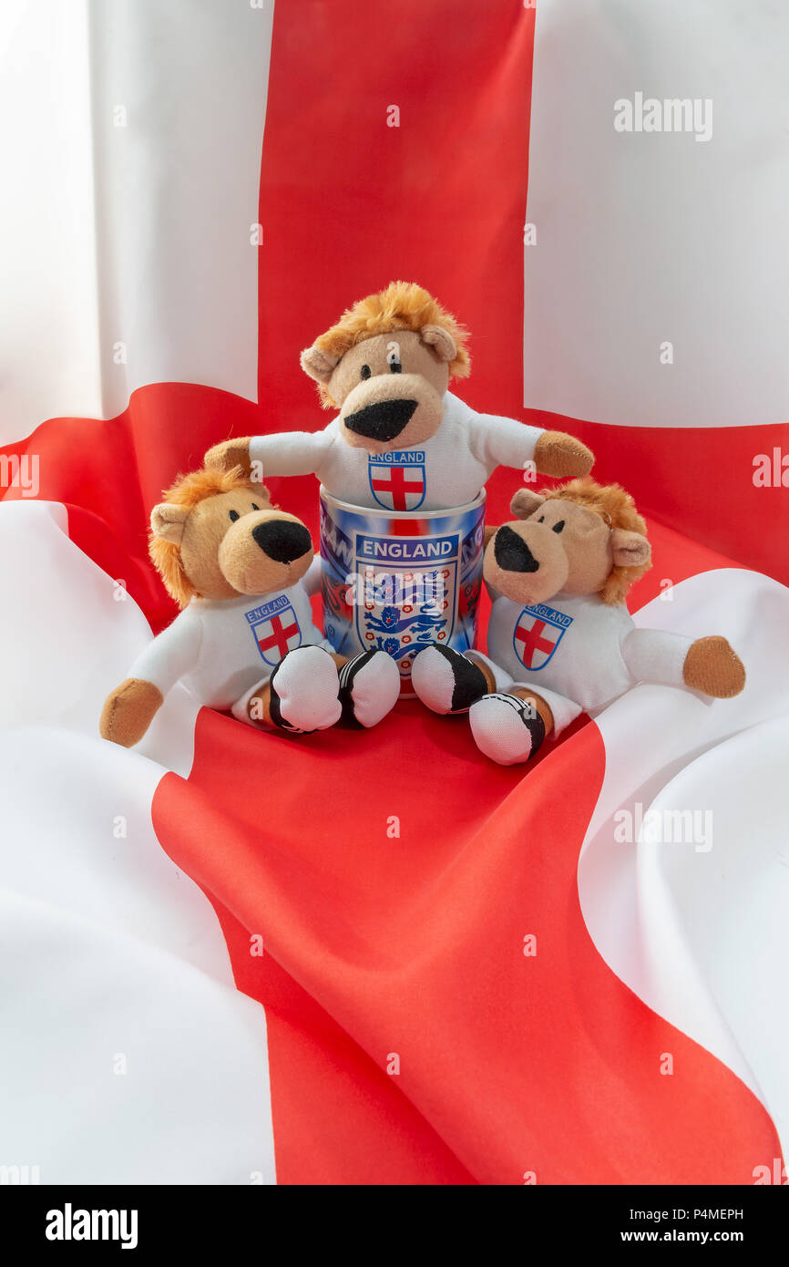Three lions sit in and around an England mug with a St George's Cross flag as a background Stock Photo