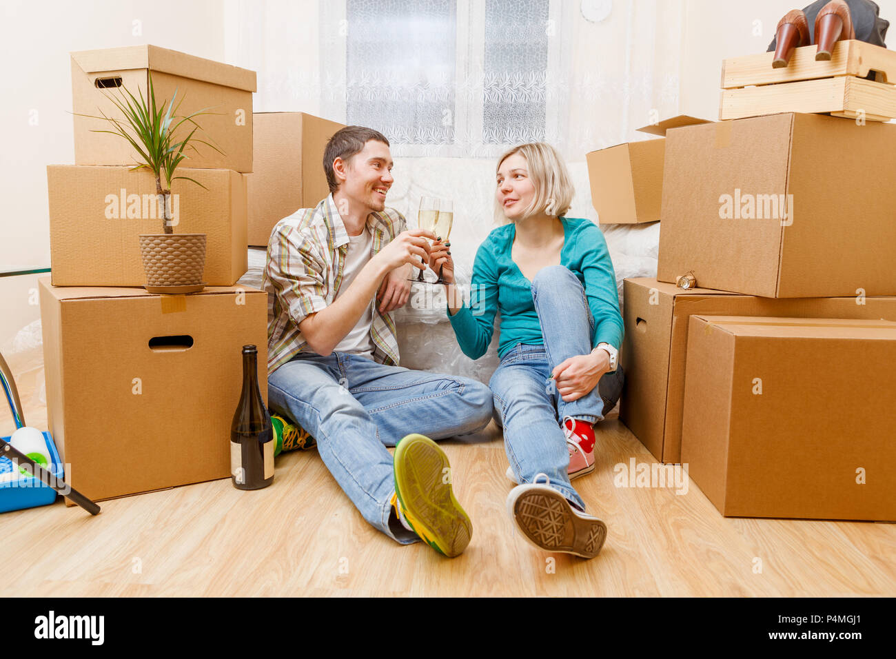 Photo of man with bottle of wine and woman sitting on sofa among ...