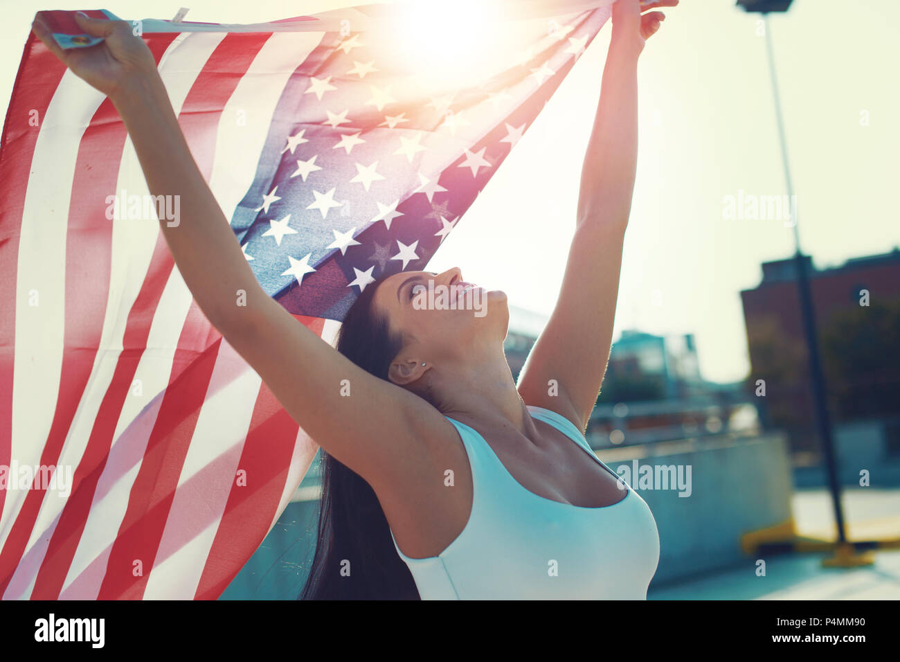 Happy young woman holding USA flag in air over head Stock Photo