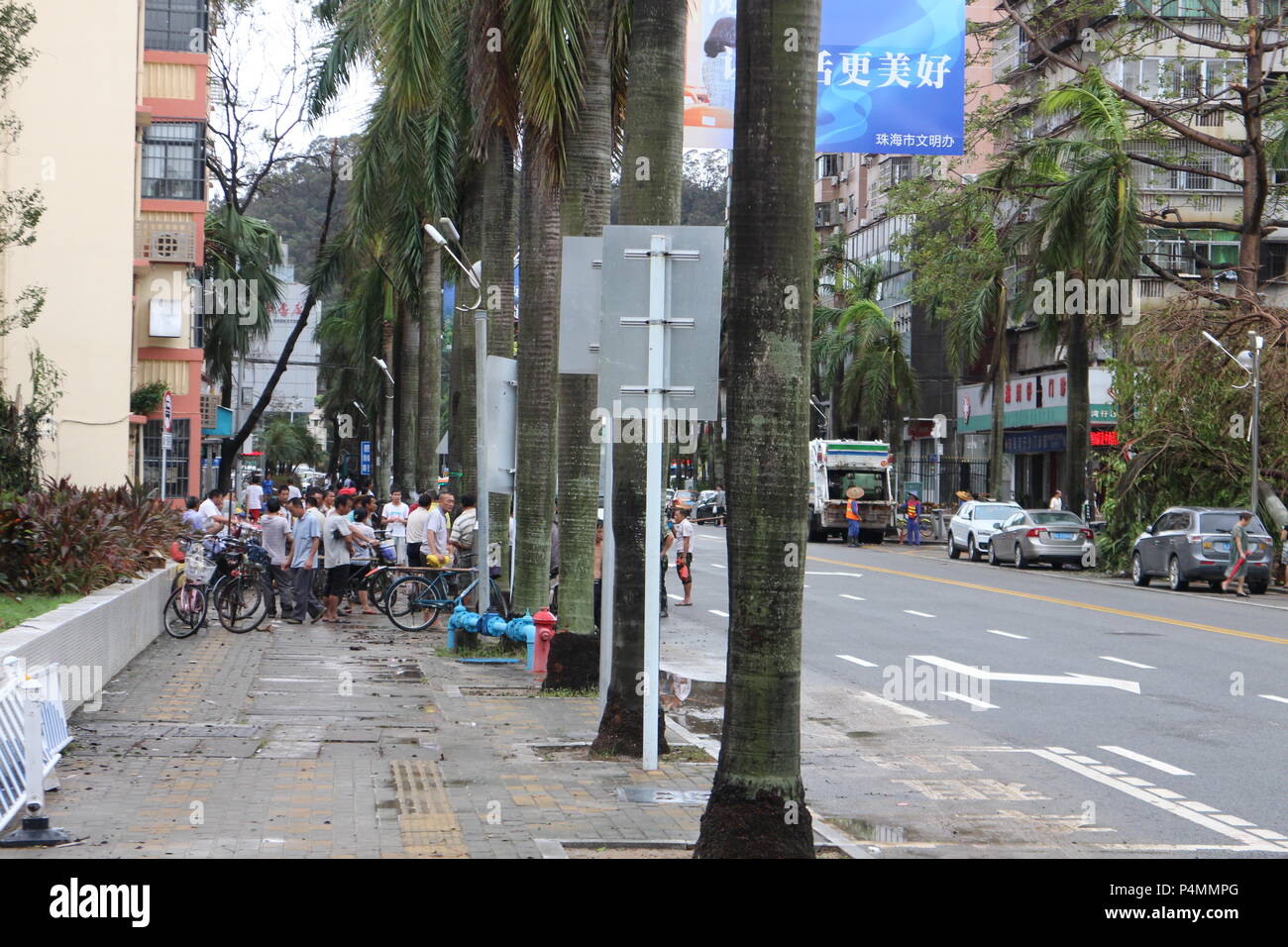 A team of workers cleaning the street after the typhoon. Hato typhoon hit the coasts of Southern China and the economic hub of Hong-Kong and Macau, killing 12 people and causing heavy material damages estimated at US$ 1.42 billion. These pictures were taken in the residential and commercial district of Wanzai sha in Zhuhai, a coastal city on the border with Macau. It shows in a concrete way the scope of the destructions, but also the resilience capacity of Zhuhai inhabitants who immediately resumed their daily activities as soon as the typhoon calmed down. Stock Photo