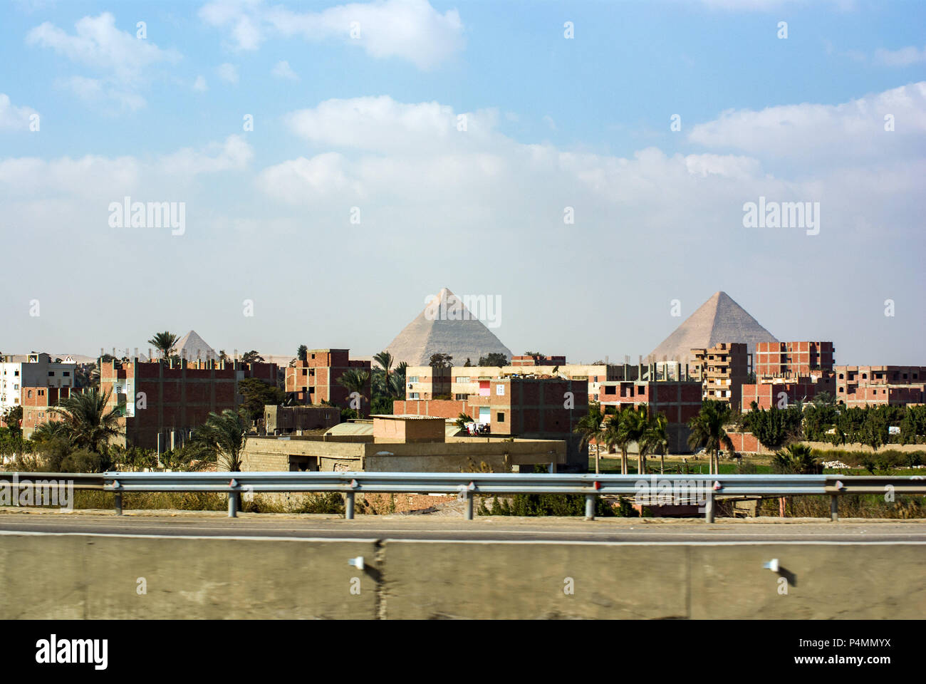 View of the pyramids of Keops, Kefren and Menkaure from the ring road of Cairo. Ahead half-built homes but with people living in them Stock Photo