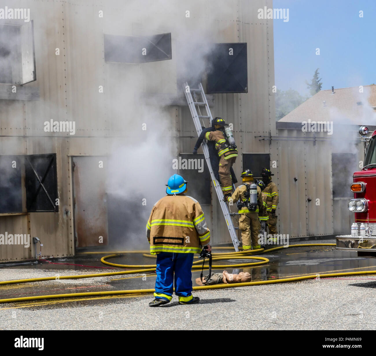 Students bringing a dummy down a ladder from a smoke house at a firefighter instuction academy. Stock Photo