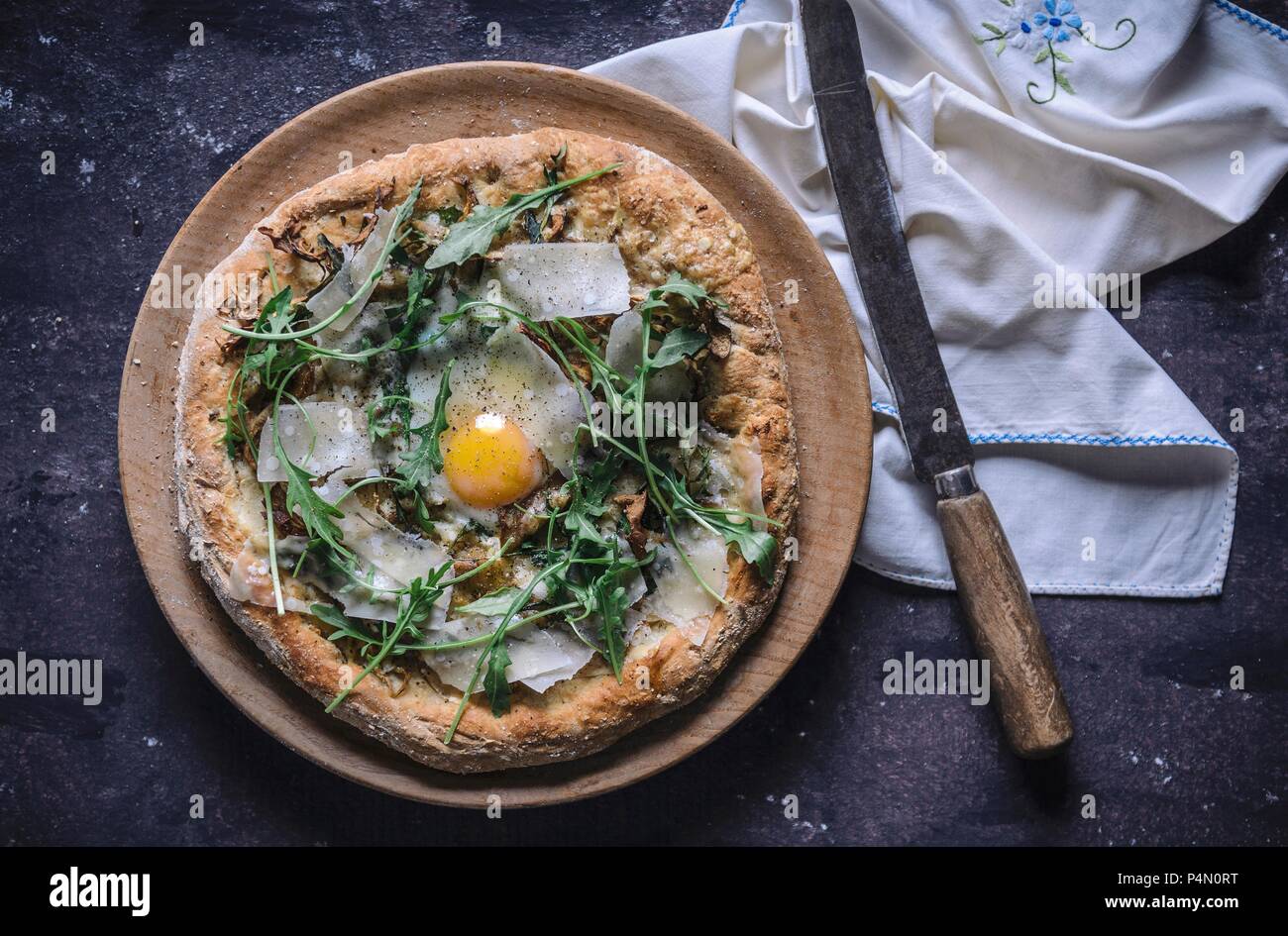 Pizza with fried egg, rocket and parmesan (top view) Stock Photo