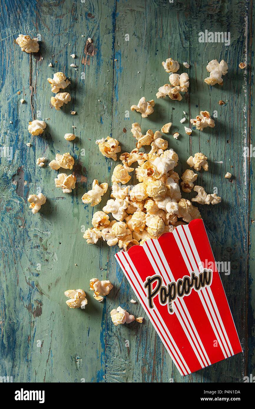 Boxed popcorn spilling out onto an aqua wooden board Stock Photo