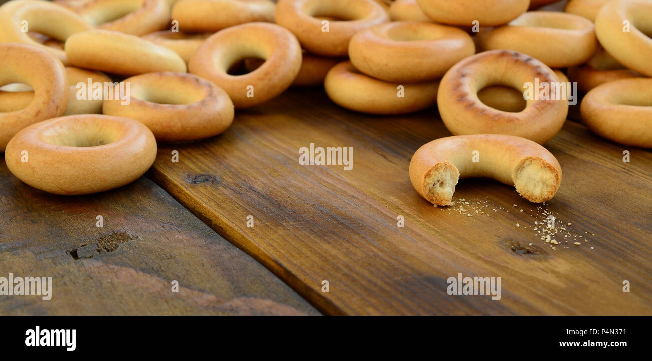 A lot of fresh yellow bagels lie on the surface of the old dark wood. A popular kind of flour products. One of the traditional Russian treats for tea Stock Photo