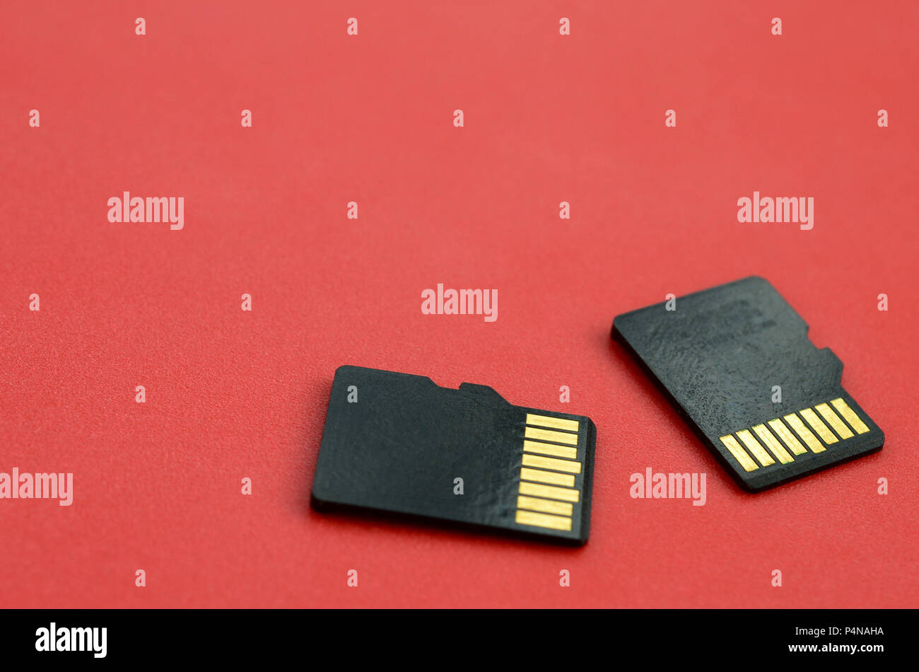 Two small micro SD memory cards lie on a red background. A small and compact data and information store . Stock Photo