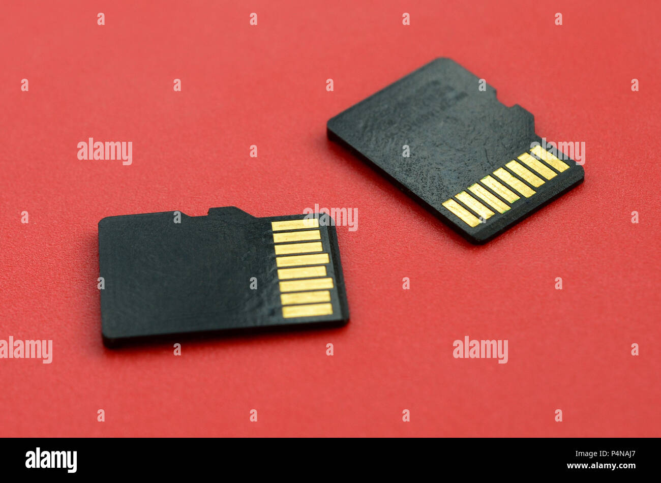Two small micro SD memory cards lie on a red background. A small and compact data and information store . Stock Photo